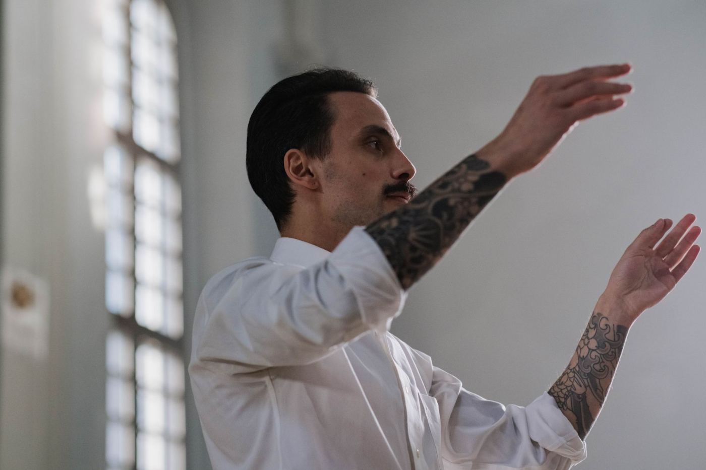 Un chef d'orchestre dirige, les mains levées