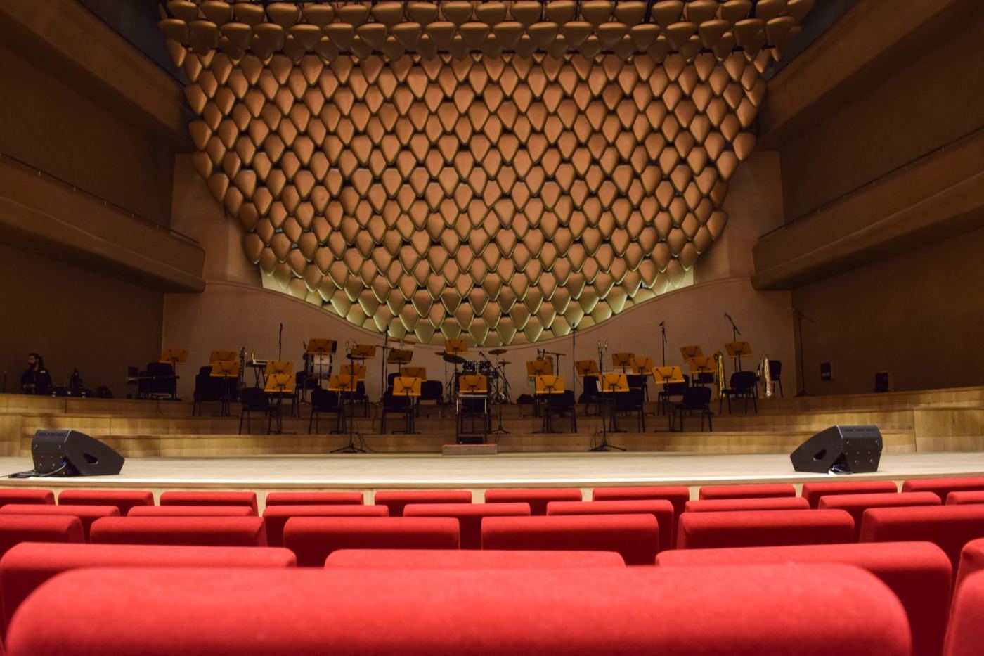 Une salle de concert vide vue depuis les fauteuils, scène éclairée